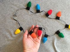 a hand holding a string of multicolored christmas lights on a gray t - shirt