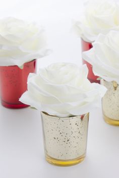 four small vases with white flowers in them