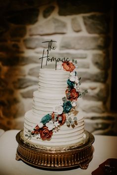 a white wedding cake with flowers and the word the thomas on it's side