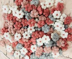 crocheted flowers are arranged on a tablecloth with branches and twigs in the background