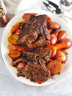 a white plate topped with meat, potatoes and carrots