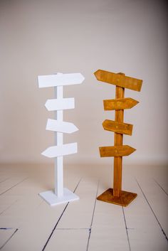 two wooden signs standing next to each other on top of a white tile floor in front of a beige wall