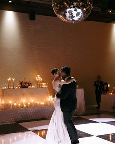 a bride and groom dance on the dance floor at their wedding reception with candles in the background