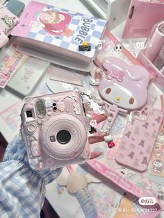 a person holding up a camera in front of a table full of hello kitty items