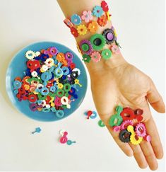 a child's hand with lots of colorful beads on it next to a bowl of sprinkles