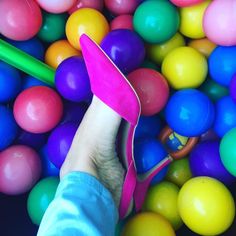 a person's feet in pink slippers surrounded by colorful balls and colored crayons