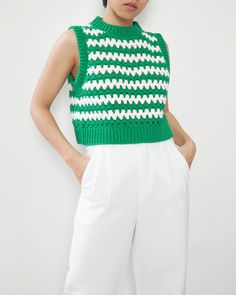 a woman is wearing a green and white knitted top with an open neckline