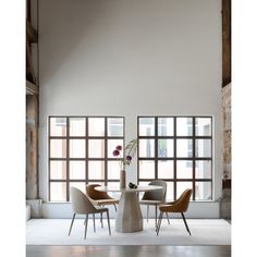 a dining room table with chairs and a vase filled with flowers on top of it