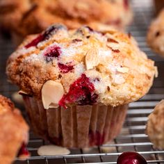 a muffin with cranberries and almonds sitting on a cooling rack next to other muffins