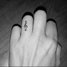 a person's hand with a small musical note tattoo on the middle finger,