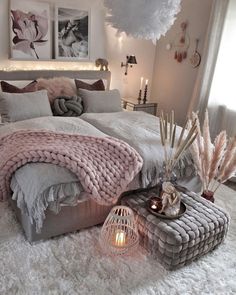 a bedroom with a large bed covered in pink blankets and pillows, surrounded by candles