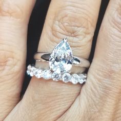 a woman's hand with a wedding ring and engagement band on top of her finger