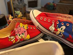 two red shoes with cartoon characters painted on them