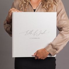 a woman holding a white box with writing on it