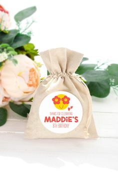 a bag that is sitting on a table with flowers in the background and a name tag for maddie's 6th birthday