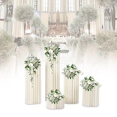 three white vases with flowers and greenery on them in front of a cathedral