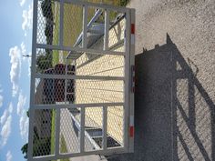 a metal gate next to a road with a red fire hydrant on the side