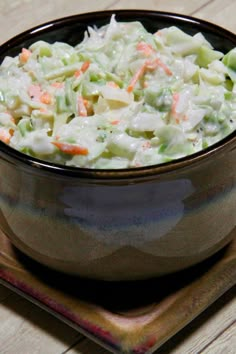 a bowl filled with coleslaw on top of a wooden table