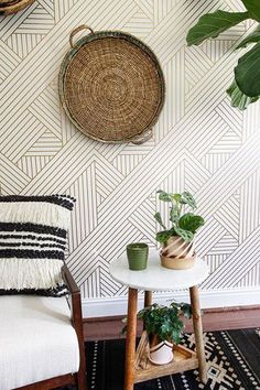 some plants are sitting on a small table in front of a wall with geometric designs