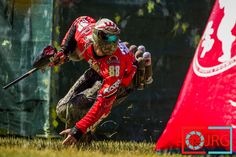 a man riding on the back of a motorcycle down a grass covered field next to a red flag