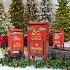 three christmas mail boxes sitting next to each other in front of trees with presents on them