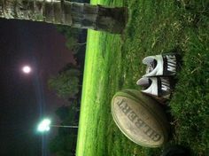 a football and shoes are laying on the ground in front of a tree at night