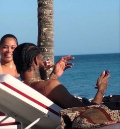 two women sitting on a beach chair next to the ocean