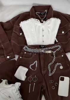 a white shirt and brown pants are laid out on top of a bed with other items