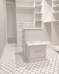 a walk in closet filled with lots of white shelves and drawers next to each other