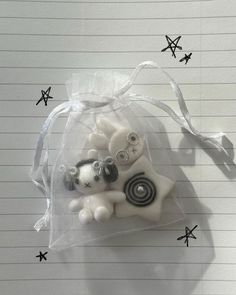 a small white bear in a clear bag on top of lined notebooks with black and white stars