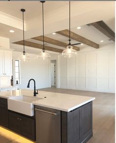 a kitchen with an island, sink and two lights hanging from the ceiling above it