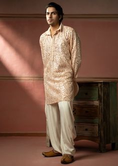 The georgette mirrorwork fabric is specially designed by our team and crafted with great care and precision. With the floating mirror effect of jaali-work, the garment is then styled at our workshop with finest details. Pink Sequined Kurta For Festivals, Silk Sherwani With Mirror Work, Pink Sherwani With Mirror Work In Straight Kurta Style, Silk Sherwani With Mirror Work In Straight Kurta Style, Silk Sherwani With Mirror Work, Straight Kurta, Pink Sherwani With Mirror Work, Elegant Peach Kurta With Resham Embroidery, Elegant Peach Kurta With Zari Work, Pink Sherwani With Mirror Work For Designer Wear