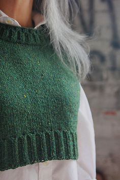 a woman with grey hair wearing a green sweater