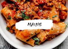 a white bowl filled with pasta covered in sauce and parsley on top of a table