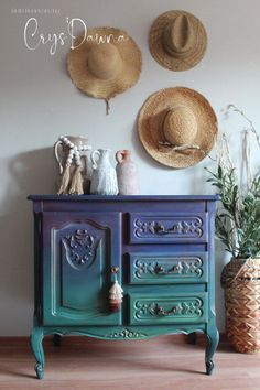 two hats are hanging on the wall next to a blue dresser with drawers and vases