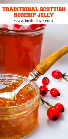 a jar filled with liquid next to some berries and a wooden spoon on a table