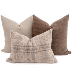 three pillows with different colors on them sitting next to each other in front of a white background