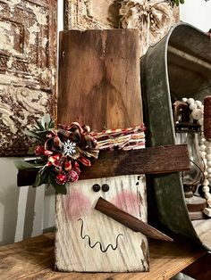 a snowman made out of wood sitting on top of a wooden table next to other items