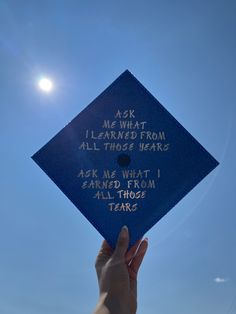 someone holding up a blue graduation cap with writing on it