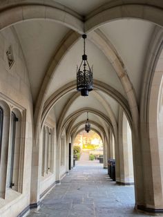 an arched walkway between two buildings with lamps hanging from the ceiling