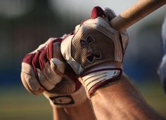 a close up of a baseball player's glove with his hand on the bat