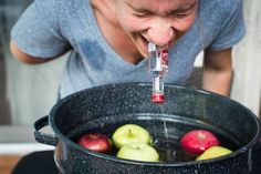 a man drinking water from a bottle in a bucket filled with apples