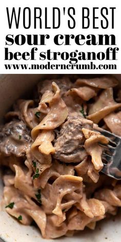 a white bowl filled with pasta and meat covered in mushroom sauce next to a fork