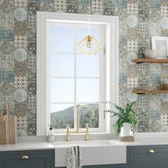 a kitchen with blue and white wallpaper, gold faucet, green cabinets and open window