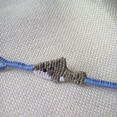 a close up of a piece of fabric on a bed with a blue and white cord