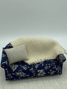 a blue and white couch with a blanket on it's back next to a pillow