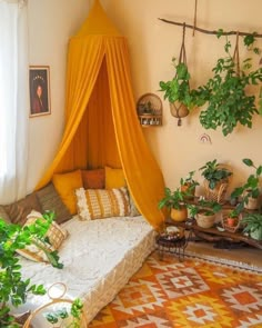 a bed with a canopy over it in a room filled with plants and potted plants