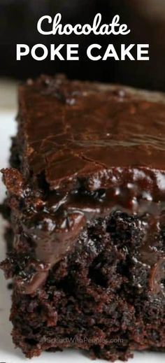 a close up of a piece of chocolate poke cake on a plate with the rest of the cake in the background