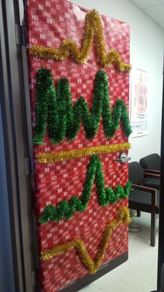 the door is decorated with red and green yarn, gold trimmings and letters that spell out love