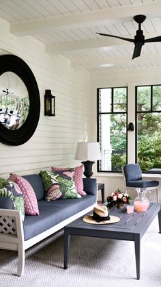 a living room filled with furniture and a large mirror on the wall above it's windows